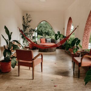 Serene indoor patio featuring a hammock, lush green plants, and comfortable seating for relaxation.