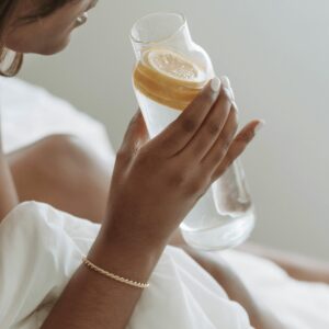 A woman holding a glass of lemon water, embodying a healthy lifestyle and relaxation.